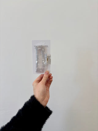A hand holding a rectangular-shaped hair clip in a translucent green color.