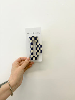 Hand holding a package of checkered hair clips with 'Stitch & Stone' branding on a white background.