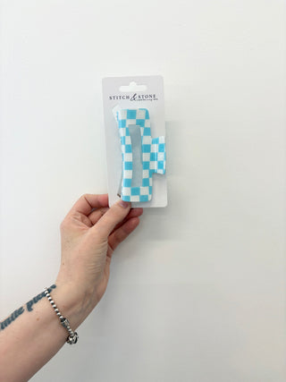 Hand holding a blue and white checkered product in packaging with 'Stitch & Stone' branding on a white background.