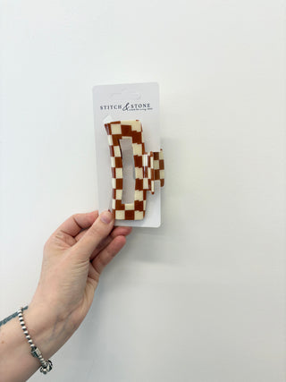 Hand holding a package of checkered hair clips with 'Stitch & Stone' branding on a white background.