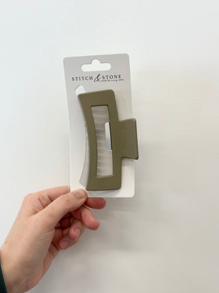 Hand holding a beige tool with 'Stitch & Stone' packaging on a white background