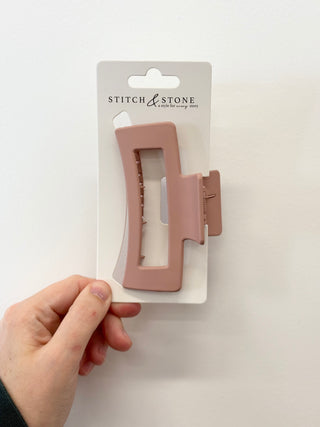 Pink hair clip on a 'Stitch & Stone' branded card held by a hand against a white background