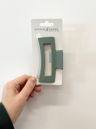 Hand holding a green tool on a white background with 'Stitch & Stone' packaging.