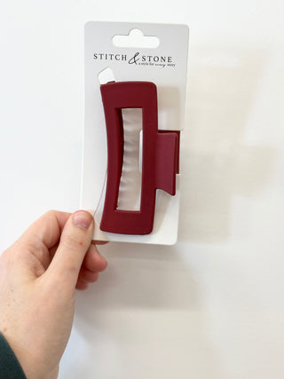 Red hair clip held by a hand against a white background with 'Stitch & Stone' packaging.