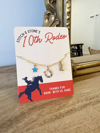Necklace with charms on a 'Stitch & Stone's 10th Rodeo' card with decorative background