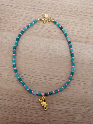 Necklace with green, pink, and gold beads on a wooden surface