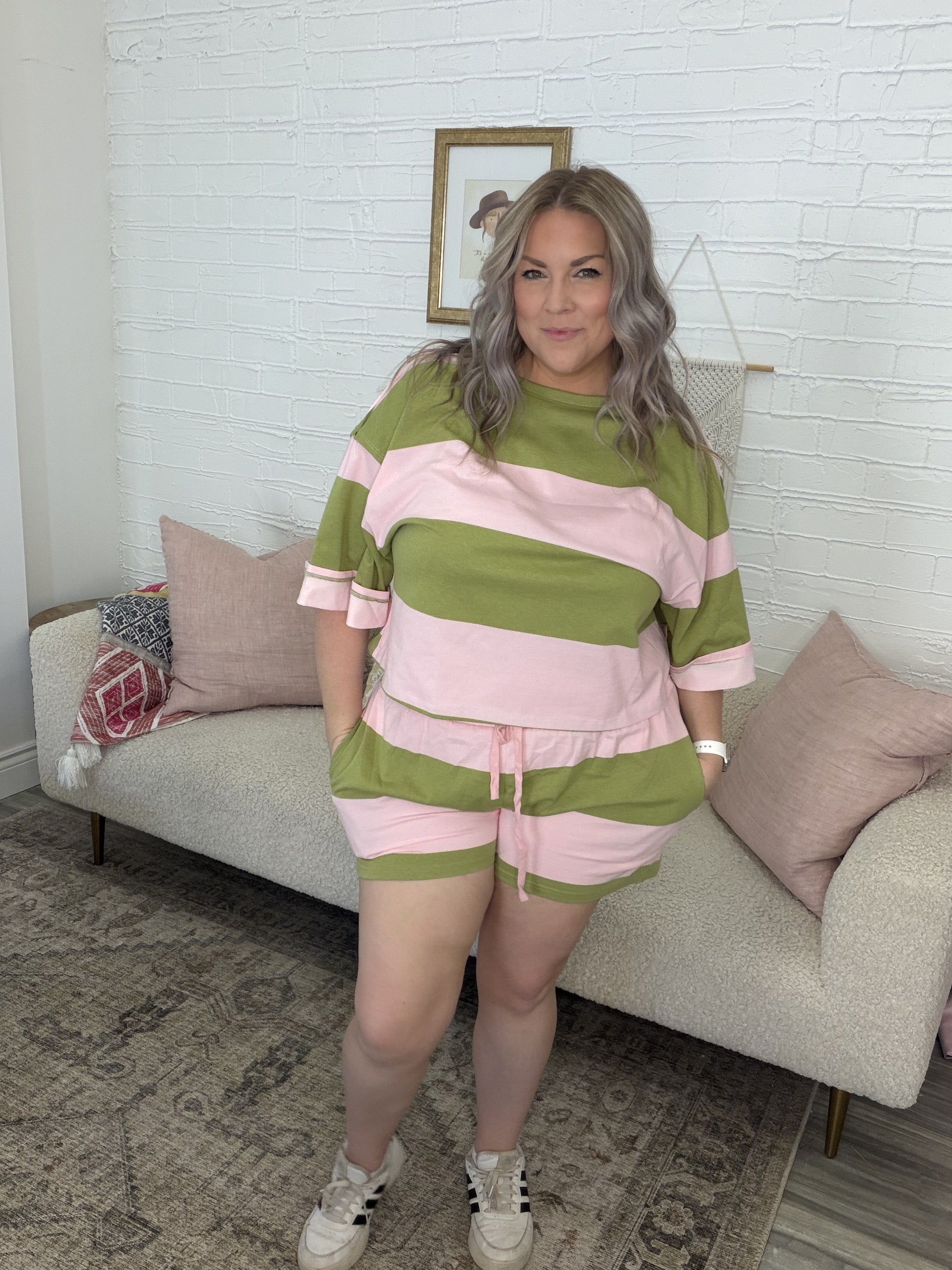Woman wearing a green and pink striped outfit standing in a living room.