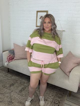Woman wearing a green and pink striped outfit standing in a living room.