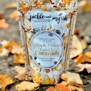 Packaging of Maple Cookie Crunch Caramels with autumn leaves on a stone surface.