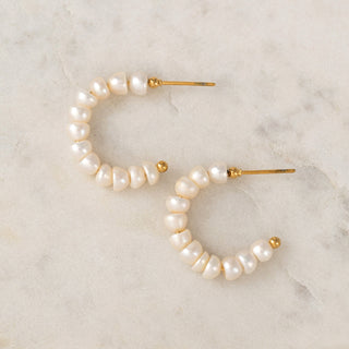 Pearl hoop earrings on a marble surface