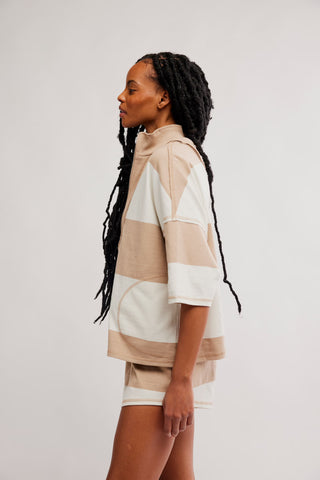Woman wearing a beige and white striped outfit on a plain background