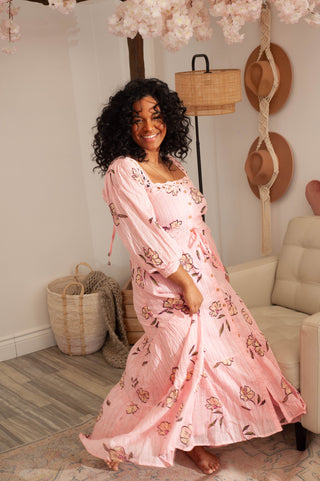 Woman in a pink floral dress sitting on a couch in a cozy living room.