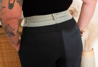 Person wearing black pants with a tattooed arm visible