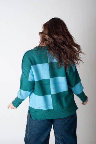 Person wearing a green and blue checkered sweater against a white background