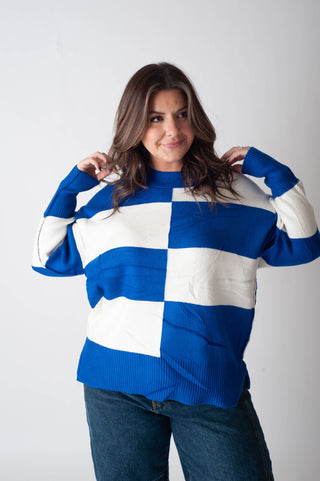 Woman wearing a blue and white checkered sweater against a plain background
