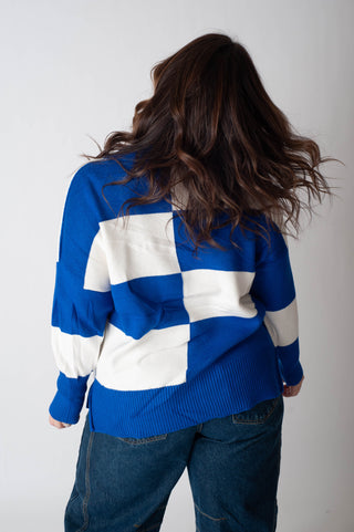 Person wearing a blue and white checkered sweater against a plain background