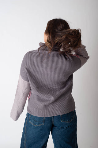Person wearing a gray sweater and blue jeans against a white background