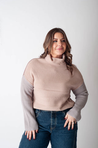 Woman wearing a beige sweater with a cutout design on a white background