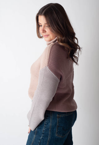 Woman wearing a two-tone sweater with a plain background