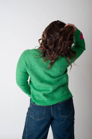 Person wearing a green sweater and blue jeans against a white background