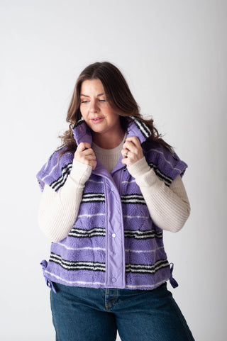 Woman wearing a purple vest with striped pattern on a white background
