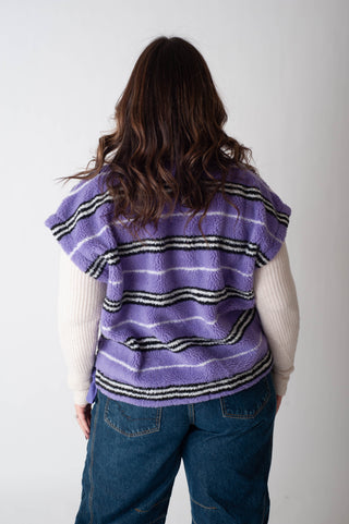 Person wearing a purple striped vest with a plain background