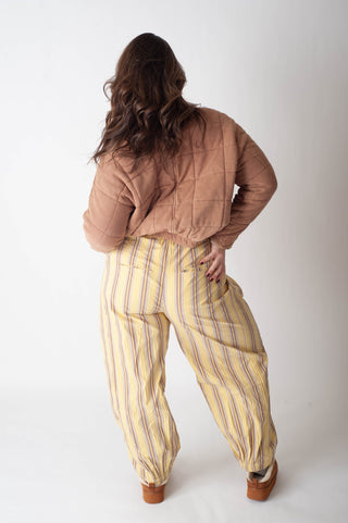 Person wearing a brown top and yellow striped pants on a white background
