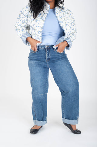 Person wearing a floral jacket, light blue top, and jeans on a white background