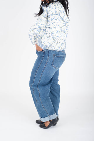 Person wearing a floral jacket and blue jeans on a white background