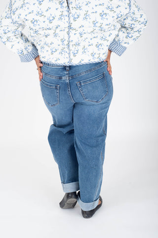 Person wearing a floral shirt and blue jeans on a white background