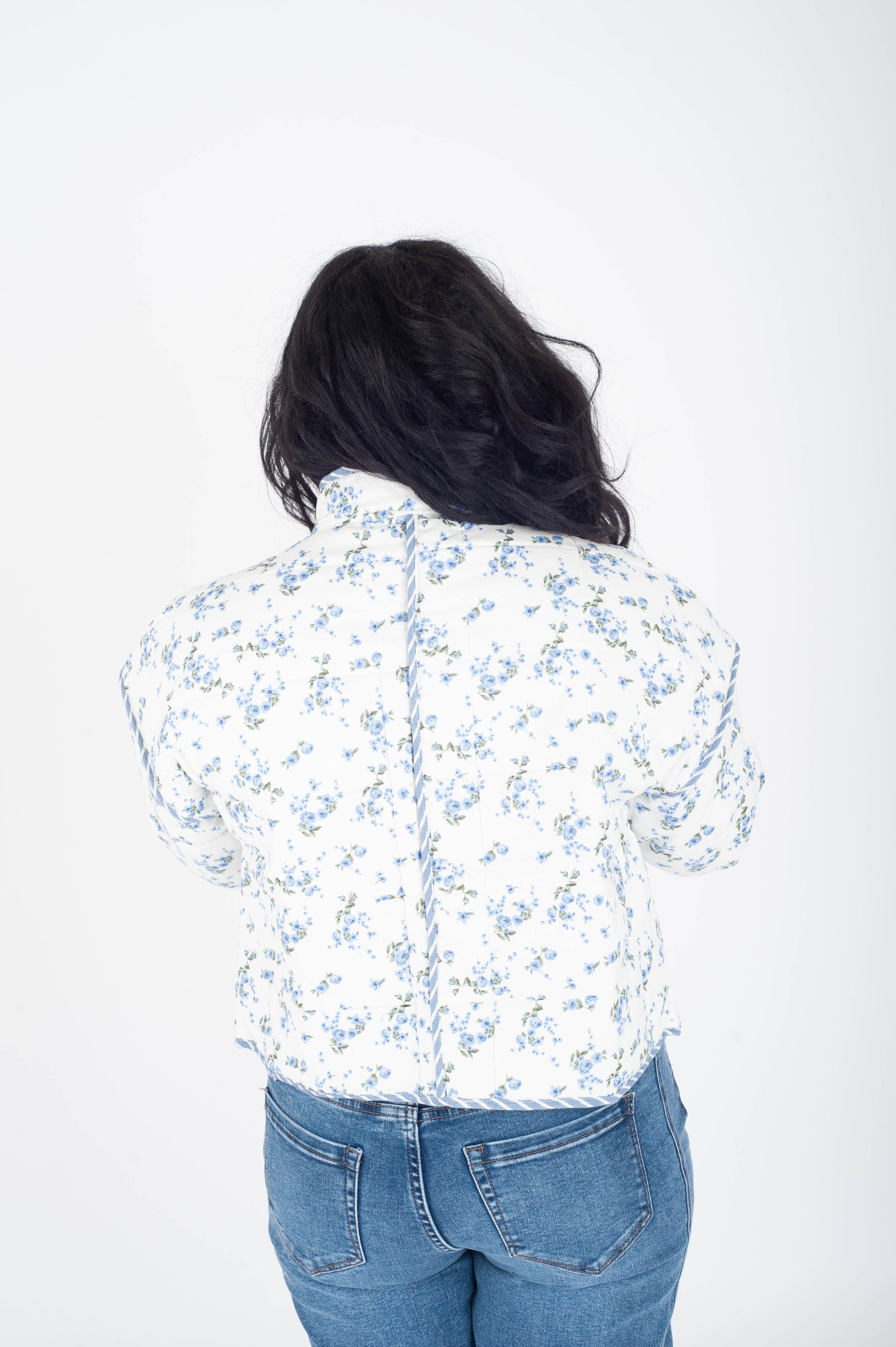 Person wearing a white floral shirt and blue jeans on a white background