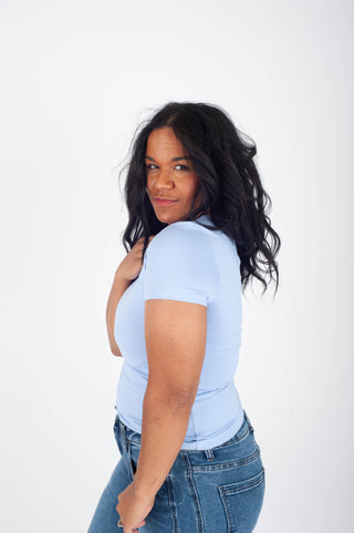 Woman wearing a light blue t-shirt and jeans on a white background