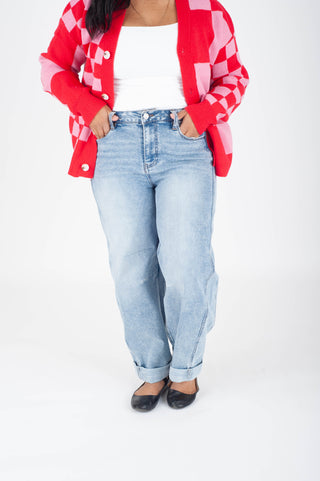 Person wearing a red and white checkered shirt over a white top with light blue jeans on a white background