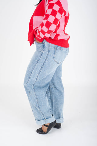 Person wearing a red checkered shirt and light blue jeans on a white background