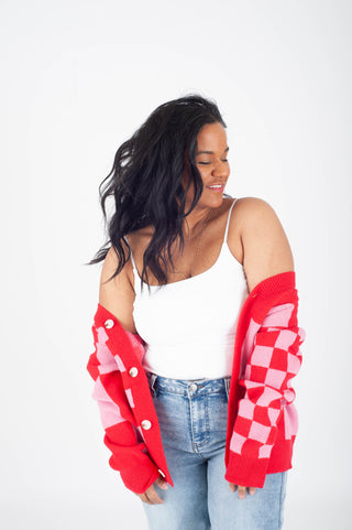 Woman wearing a red and white checkered cardigan over a white top and blue jeans on a white background