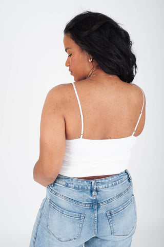 Woman wearing a white top and light blue jeans on a white background
