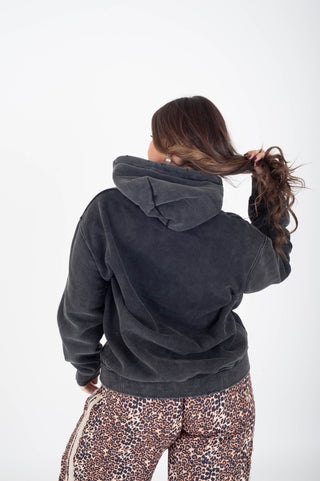 Person wearing a dark gray hoodie and patterned pants on a white background