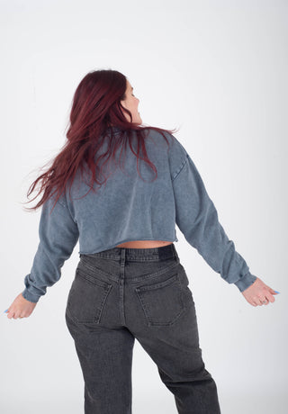 Person wearing a blue denim jacket and dark jeans on a white background