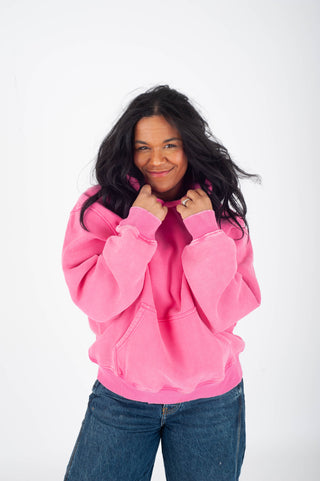 Person wearing a pink hoodie and blue jeans on a white background