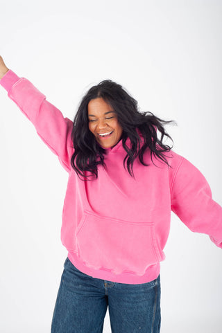 Person wearing a pink hoodie and blue jeans on a white background