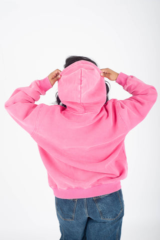 Person wearing a pink hoodie with the hood up on a white background