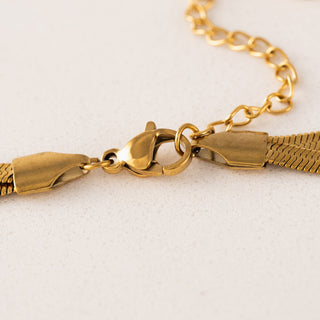 Gold bracelet on a light gray background