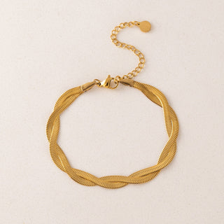 Gold braided bracelet on a light beige background
