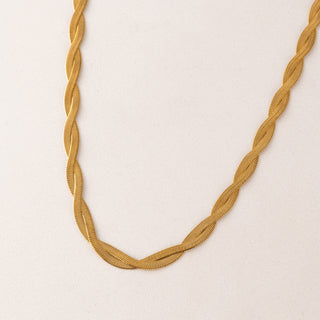 Gold braided necklace on a beige background