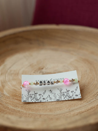 a beaded bracelet  that says be real