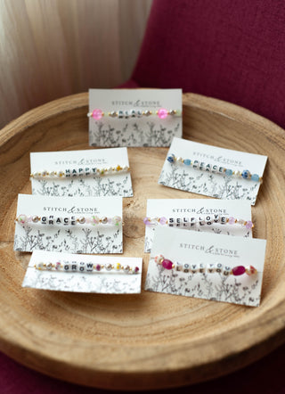 Collection of Stitch & Stone jewelry cards with various necklaces on a wooden surface.