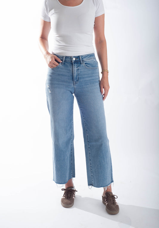 Person wearing light blue jeans and a white t-shirt on a white background