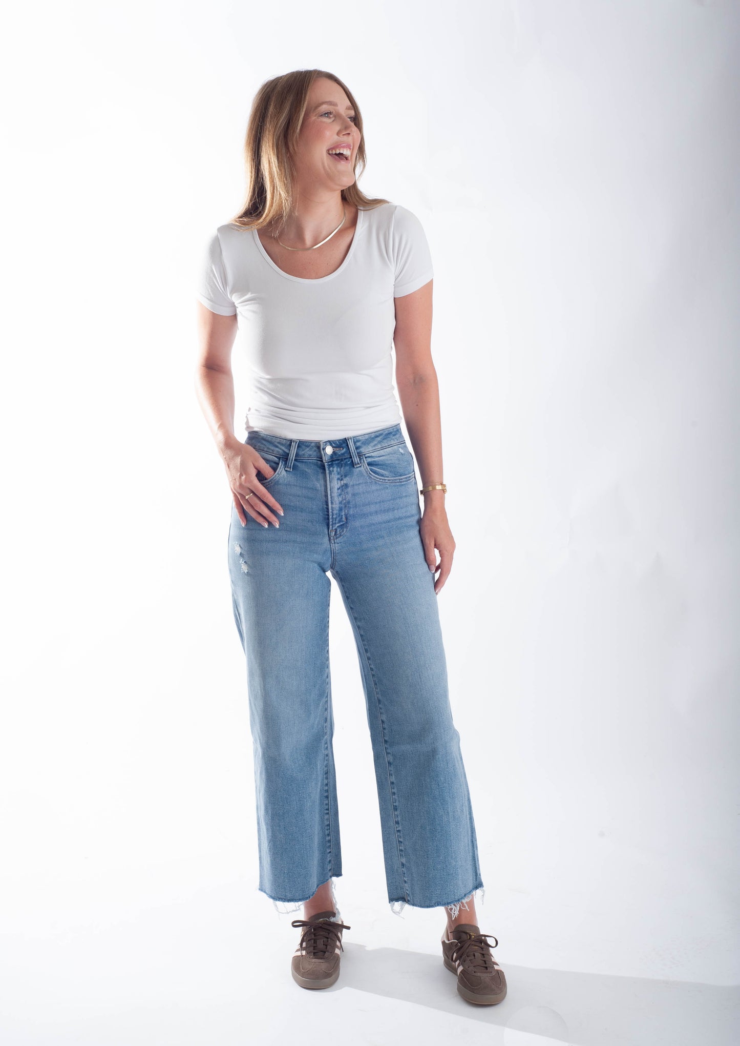 Woman wearing a white t-shirt and light blue jeans on a white background