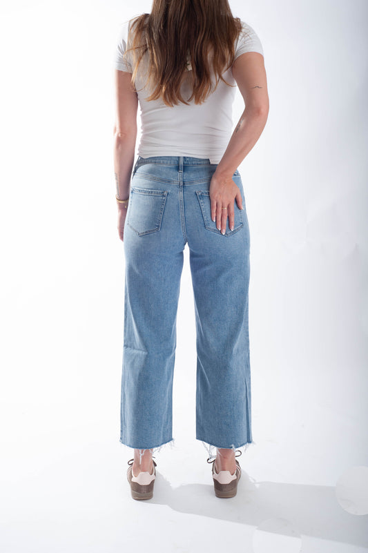 Person wearing light blue jeans and a white top on a white background