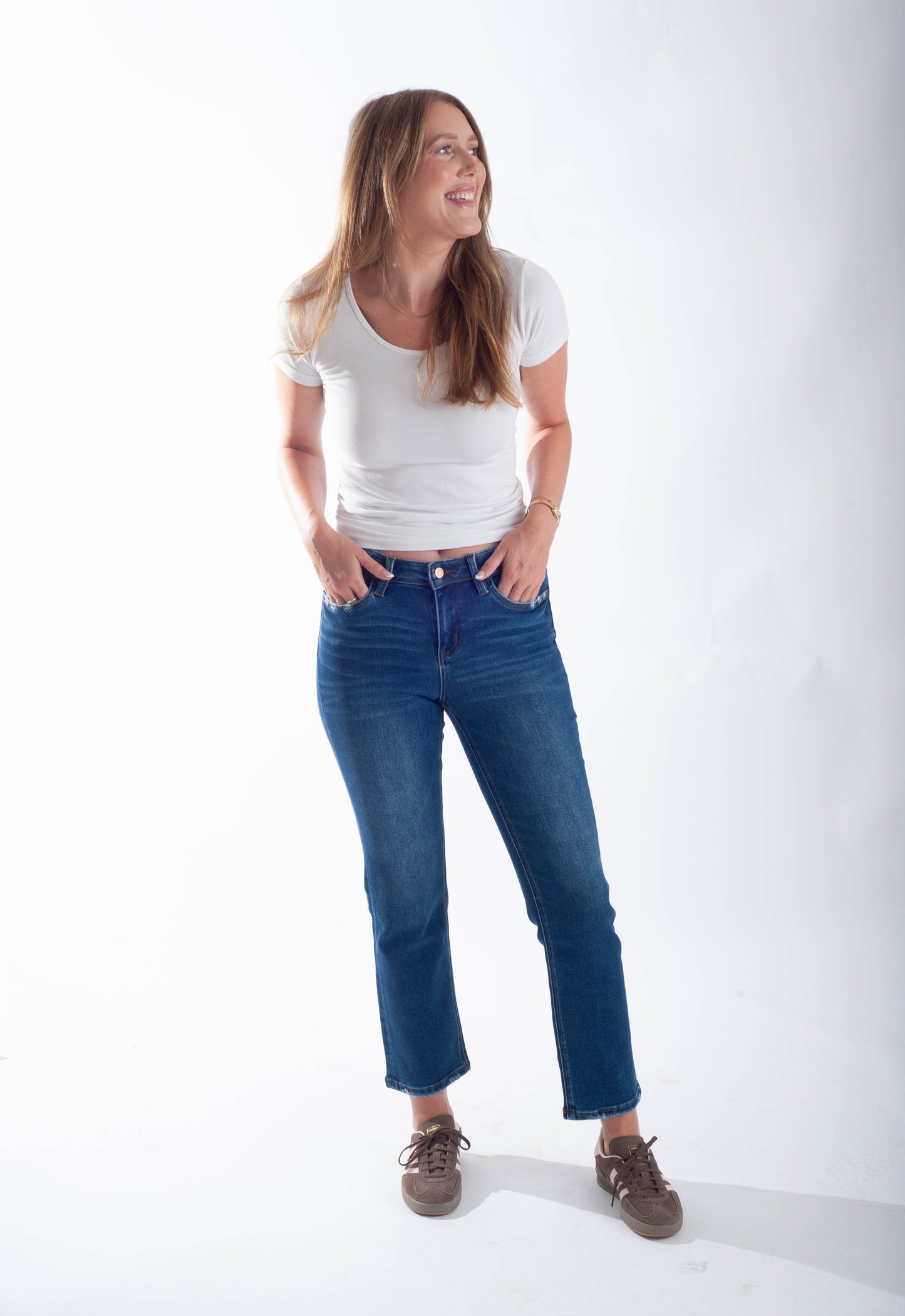 Woman wearing a white t-shirt and blue jeans standing against a white background